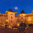 Illuminated castle on sandy hills under twilight sky