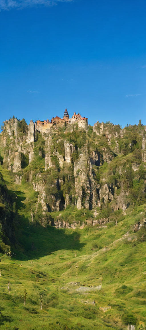 Medieval castle on rocky cliffs above green valley