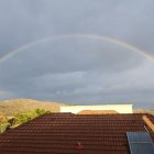 Scenic coastal village with rainbow, houses, and cliff view