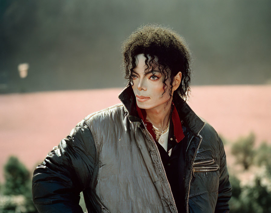 Person with Curly Black Hair in Silver Jacket and Red Shirt Staring Intently