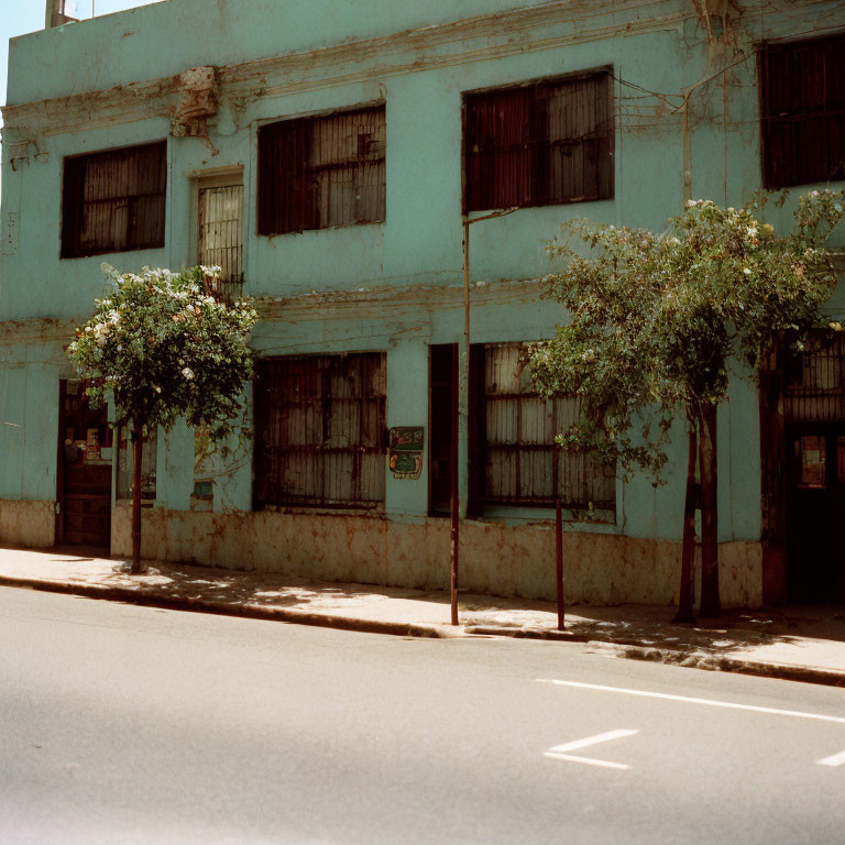 Two-story blue building with barred windows on sunny street