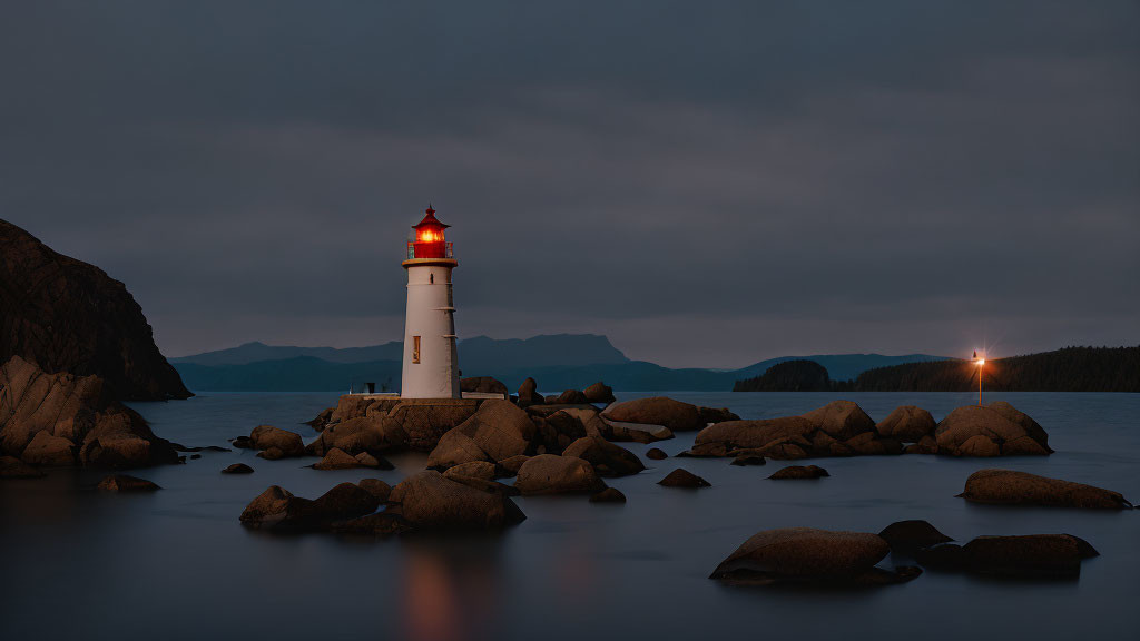 Twilight scene of illuminated lighthouse on rocky coast