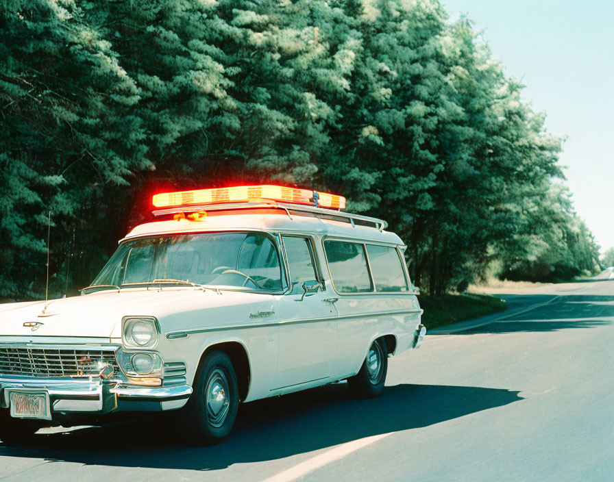 Vintage Ambulance with Flashing Lights on Green Tree-Lined Road