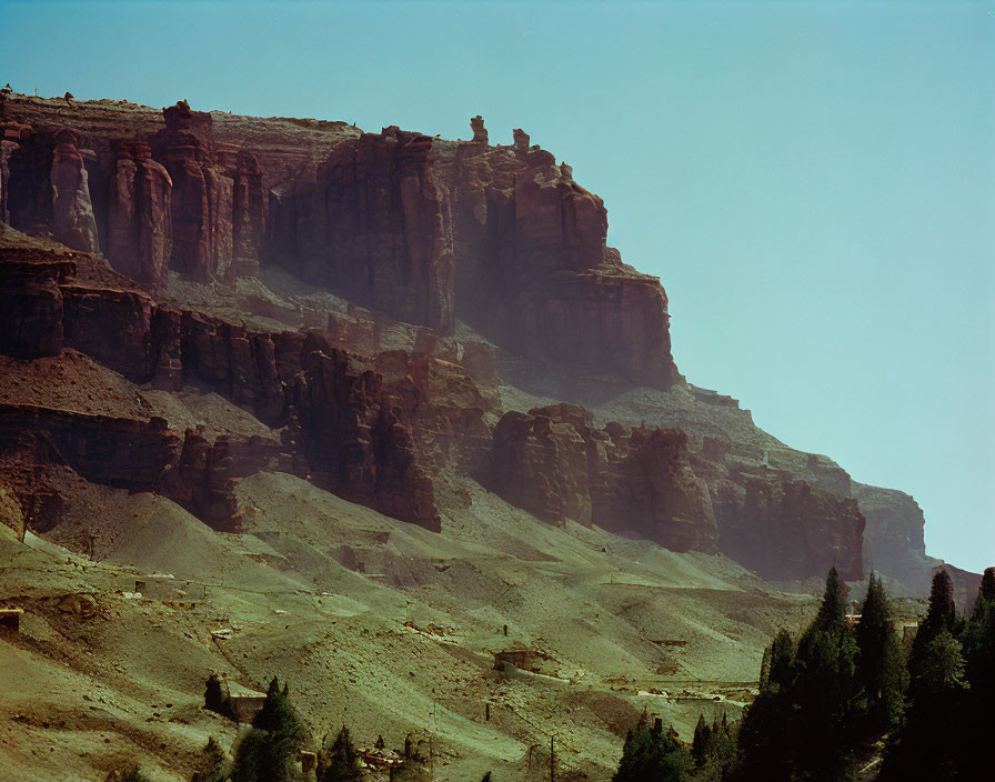 Rugged Cliff with Stratified Rock Formations under Hazy Blue Sky