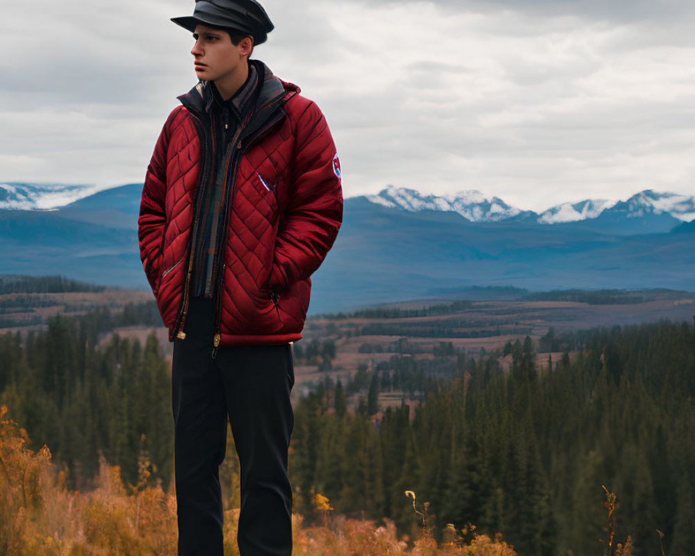 Person in Red Jacket and Hat in Autumn Field with Mountains and Cloudy Skies