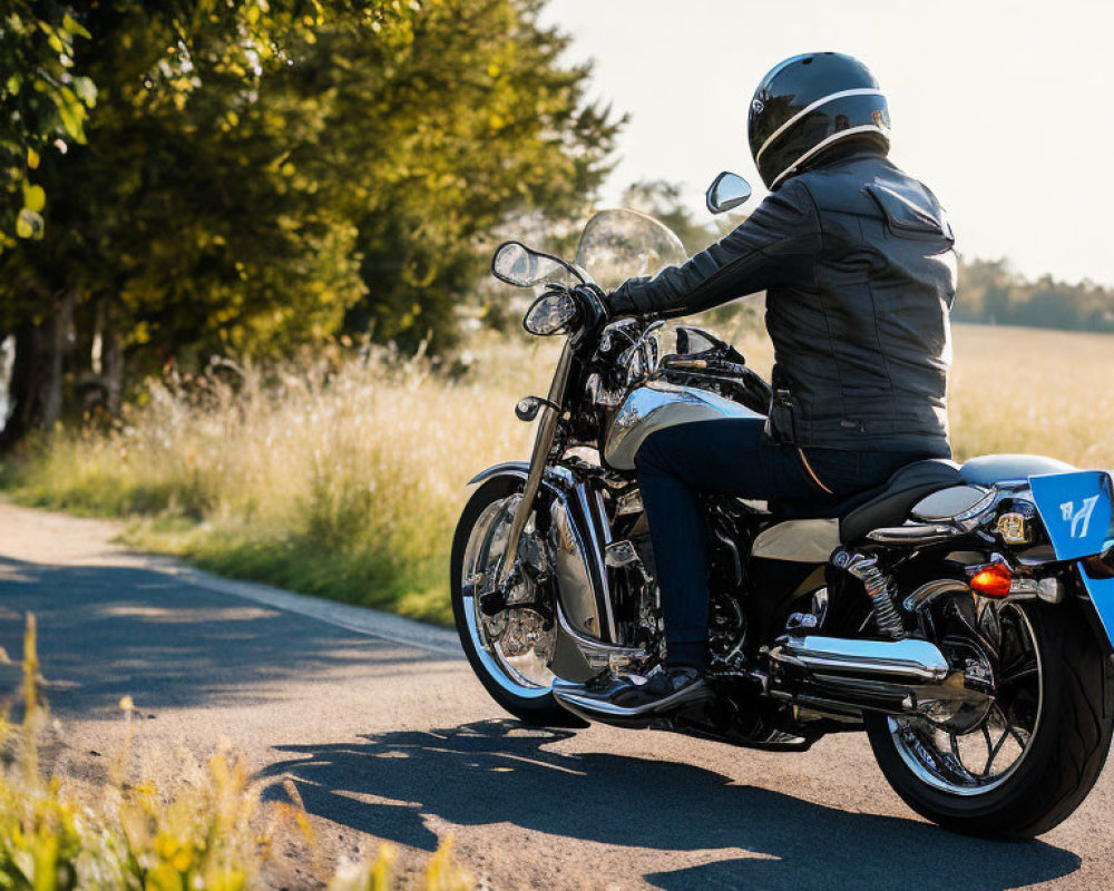 Motorcyclist in protective gear riding black cruiser motorcycle on tree-lined road