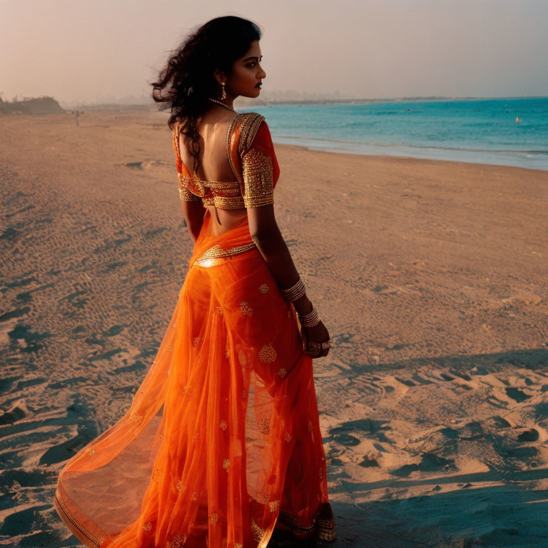 Traditional orange dress with golden embroidery on woman at beach dusk