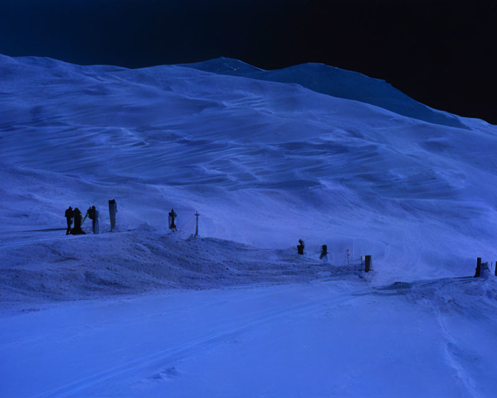 People standing on snowy mountain slope at twilight with blue-tinted snow and darkening sky