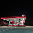 Gas Station at Night: Bright Lights, Starry Sky, Parked Car