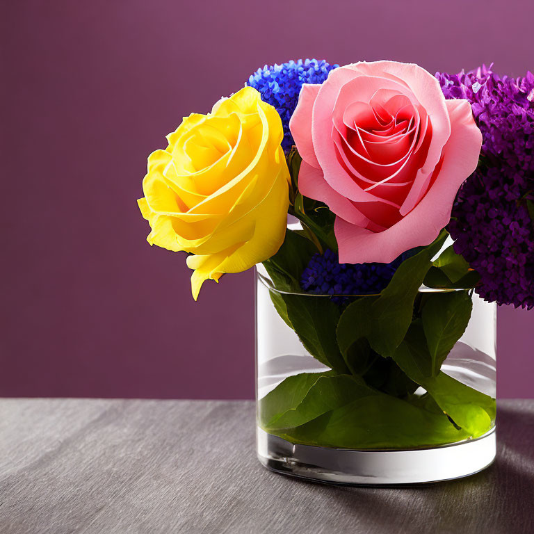 Colorful Rose Arrangement in Glass Vase with Purple Flowers and Green Leaves