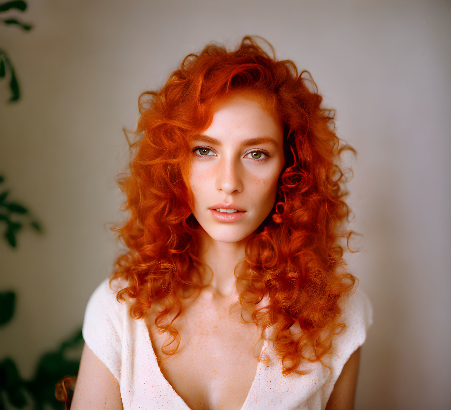 Person with Voluminous Red Hair and Fair Skin in White Top and Earrings gazes at Camera