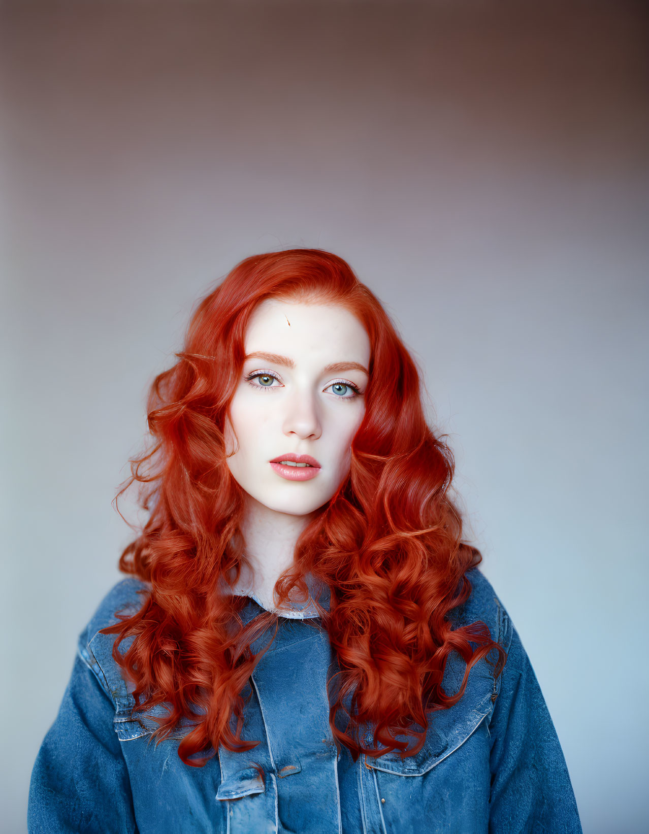 Red-haired woman in denim jacket on gradient background