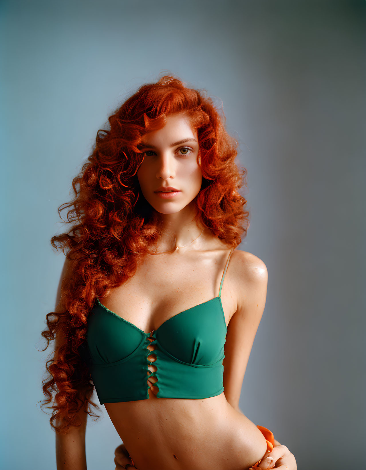 Curly Red-Haired Woman in Green Bralette on Blue Background