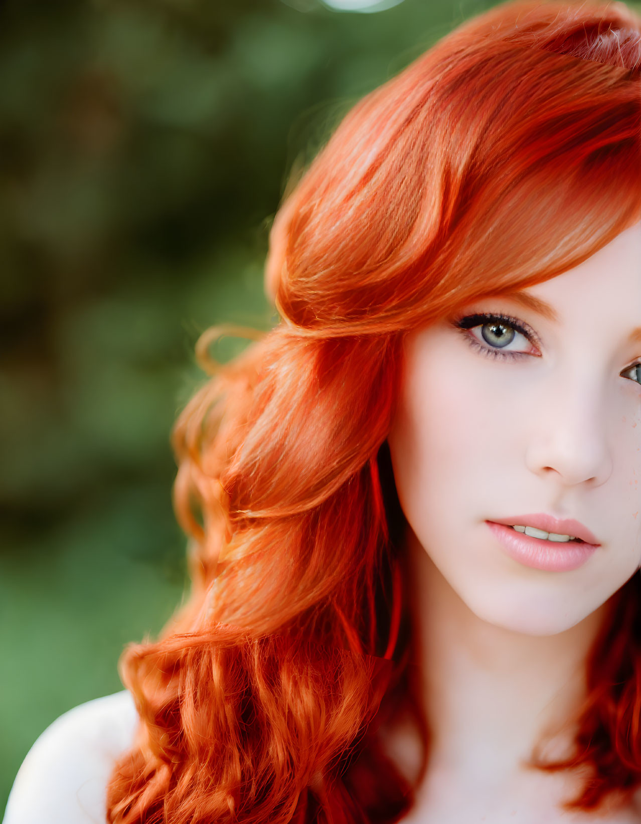 Vibrant red-haired woman with blue eyes on soft green backdrop