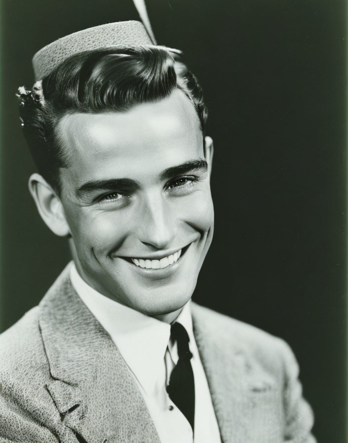 Monochrome image of smiling man in suit and tilted hat