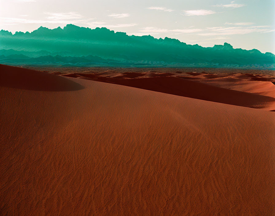 Scenic red sand dunes and distant mountains under hazy sky