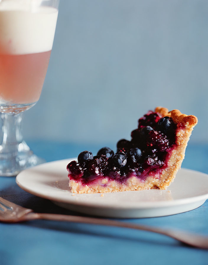 Blueberry Pie Slice with Golden Crust and Latte on White Plate