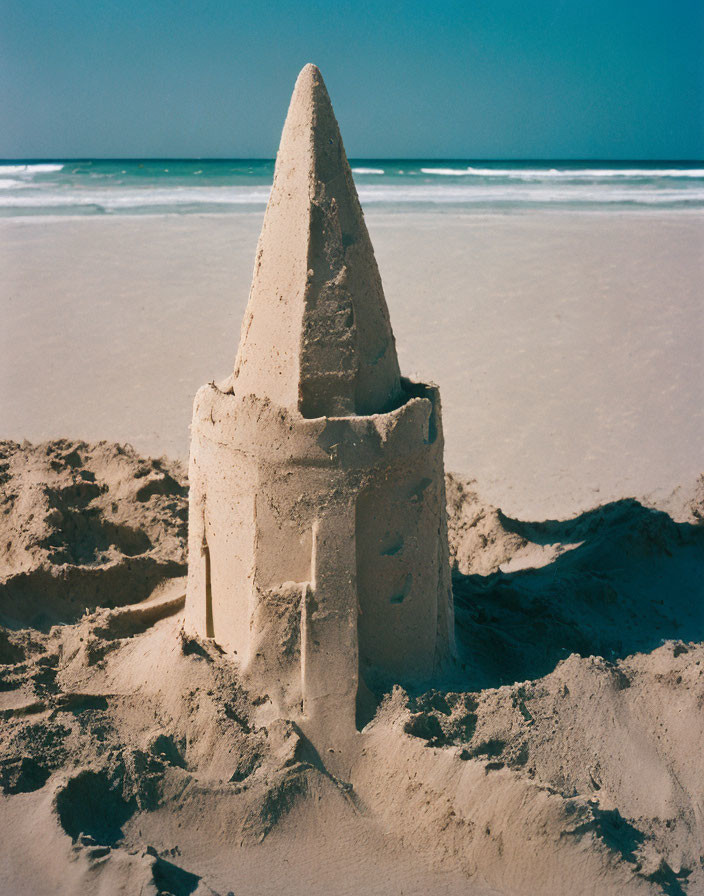 Sandcastle with central tower and surrounding walls on sunny beach