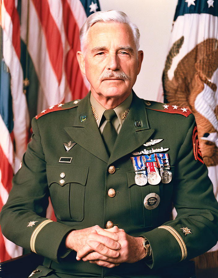 Male military officer in dress uniform with medals seated before American flag