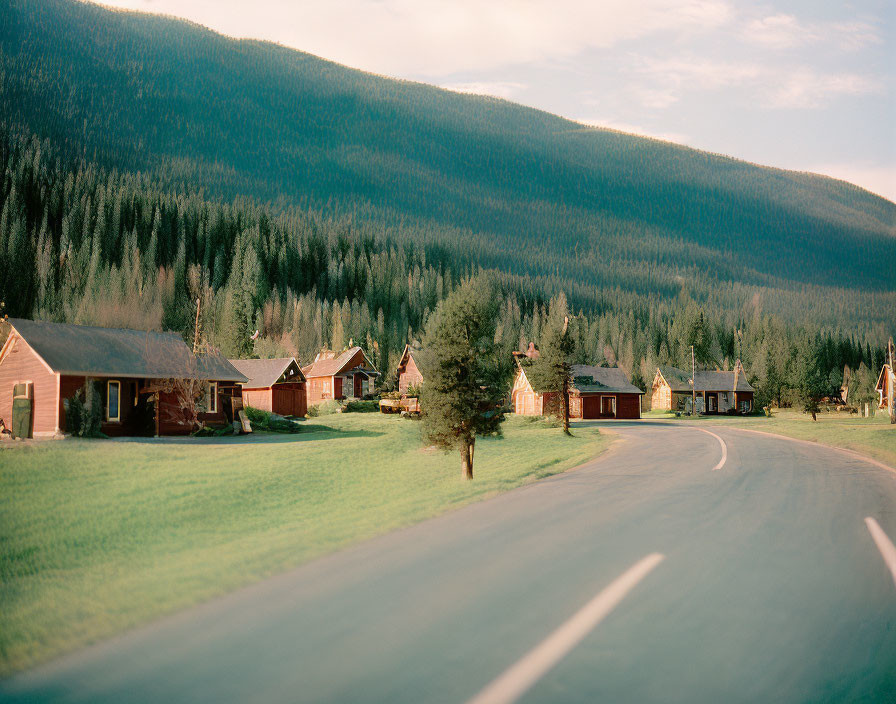 Rural scene with curving road, wooden houses, and forested hill