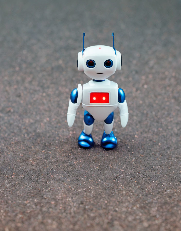 Blue and white small humanoid robot with red light and antennas on pavement