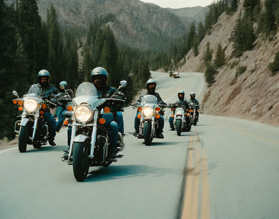 Motorcyclists in helmets ride mountain road amid forested hills