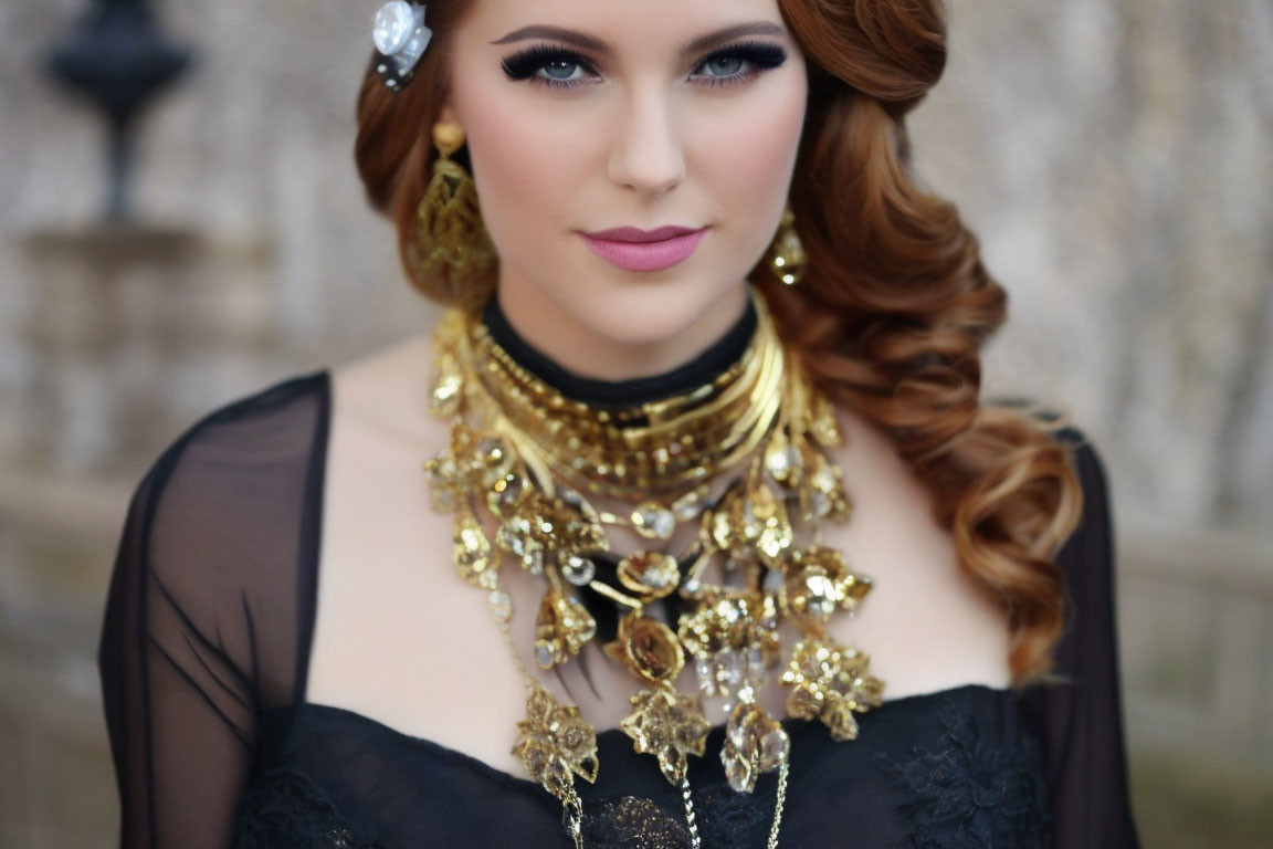 Woman with stylized makeup and curly hair wearing black outfit with gold necklace