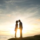 Romantic sunset kiss with heart-shaped balloons in the sky