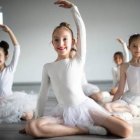 Ballet dancers in white tutus practicing in studio mirror