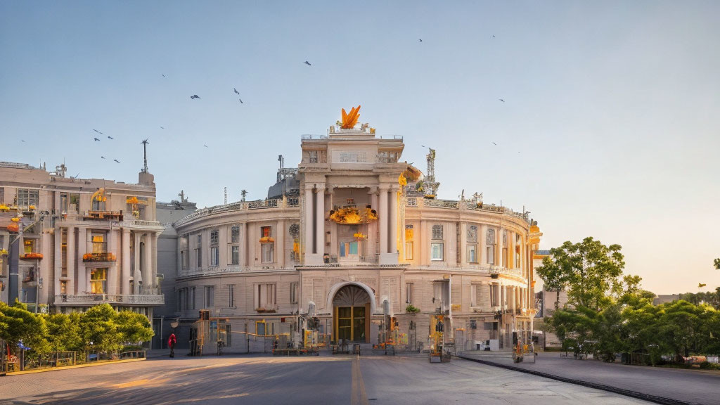 Historic building with central archway, gold-leaf sculpture, birds flying