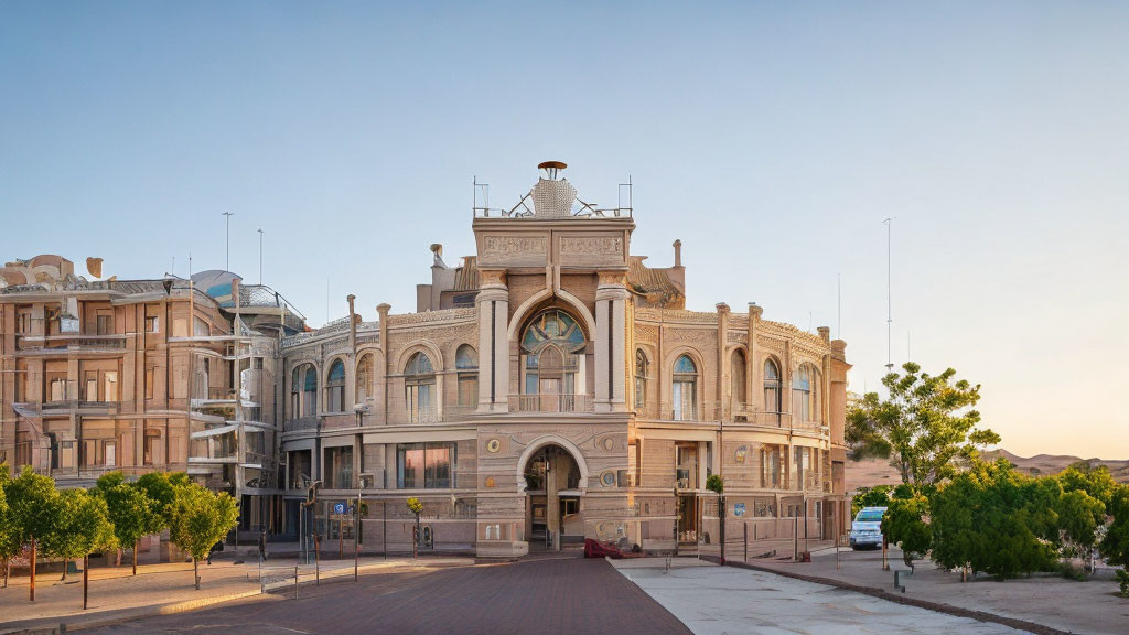 Neoclassical building with arched windows and dome, surrounded by modern structures at dawn or dusk