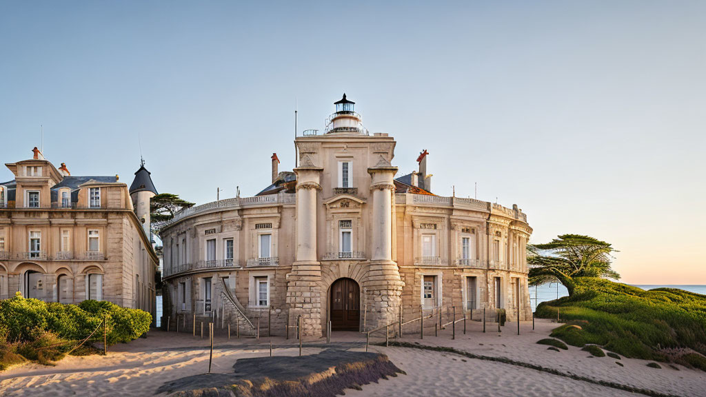 Historical building with lighthouse, sandy grounds, trees, clear sky at dawn/dusk