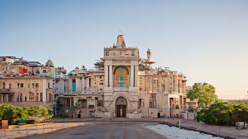 Ornate building with arched gateway amid multi-storied structures at sunrise or sunset