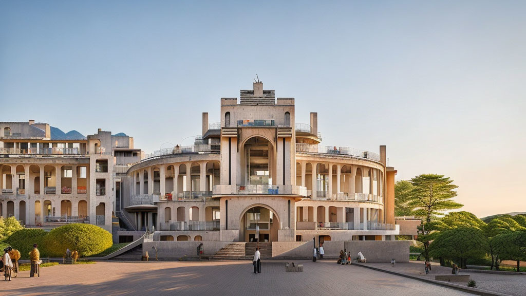 Symmetrical Art Deco concrete building with terraces, trees, courtyard, and people walking