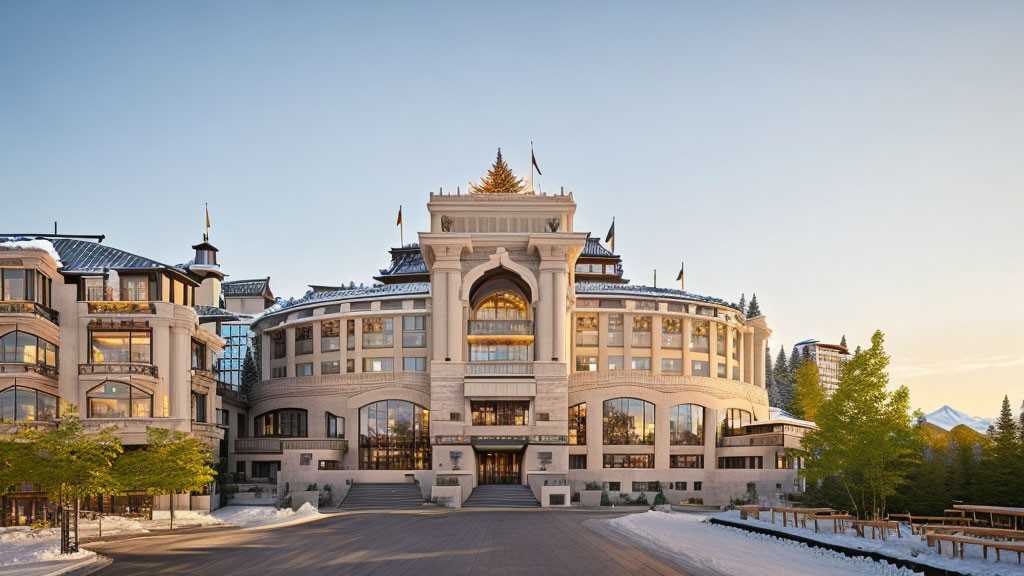 Grand snow-covered building with central peak and symmetrical wings under clear dusk sky