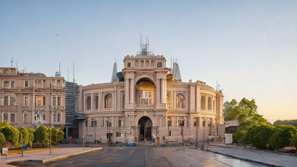 Historic building at dawn with clear sky and lit streetlamps