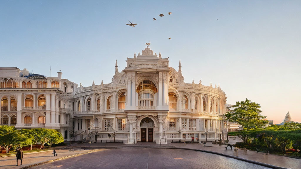 Historical white building with arched windows, birds in sky, and people outside