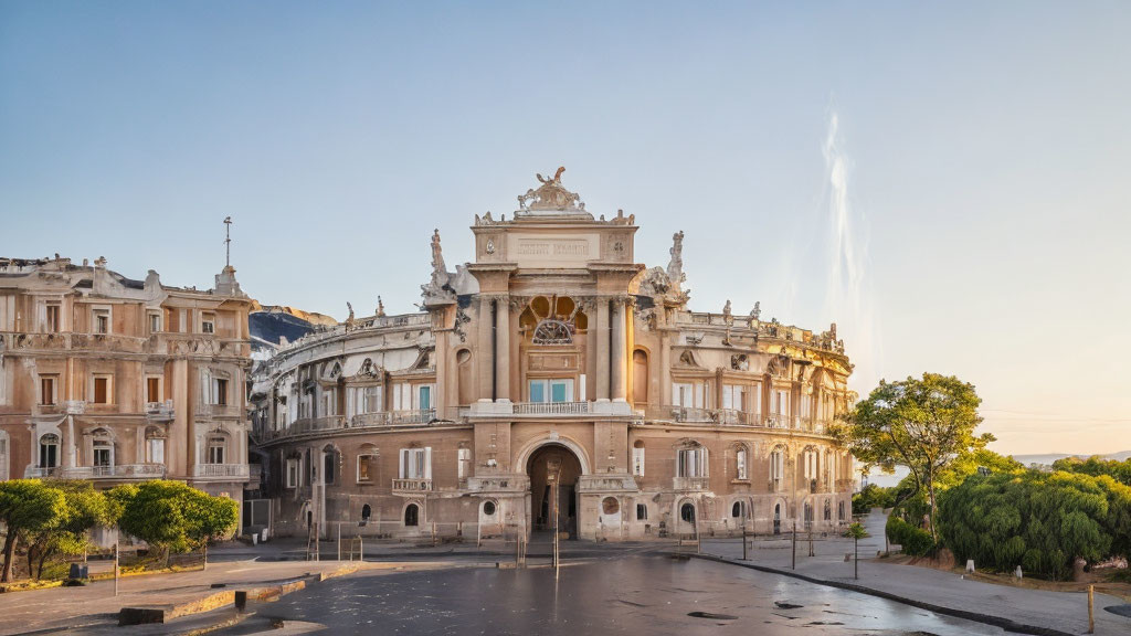 Baroque-style building with statues, arched entrance, and fountain.