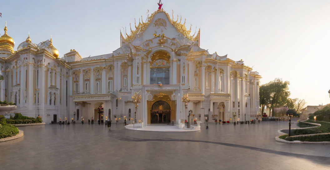 Ornate white and gold building with central entrance and spires against blue sky and greenery