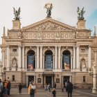 Ornate Building with Statues, Flags, and Arched Entrances