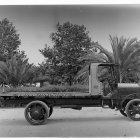 Monochromatic post-apocalyptic vehicle with oversized wheels and mechanical appendages in desolate landscape