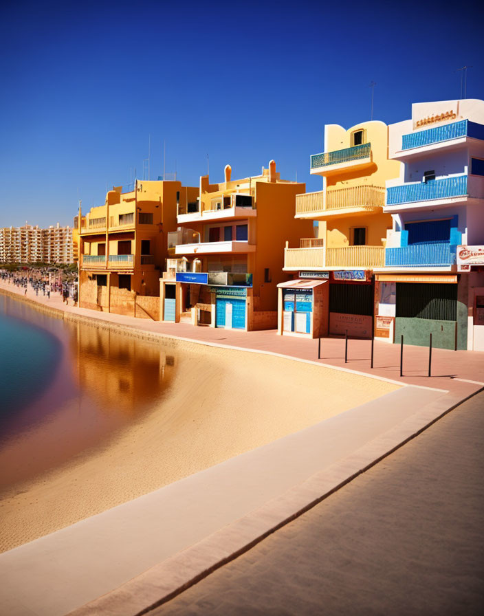 Vibrant beachfront buildings under blue sky on sandy beach.