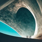 Curved concrete arch with distant building silhouette under clear sky