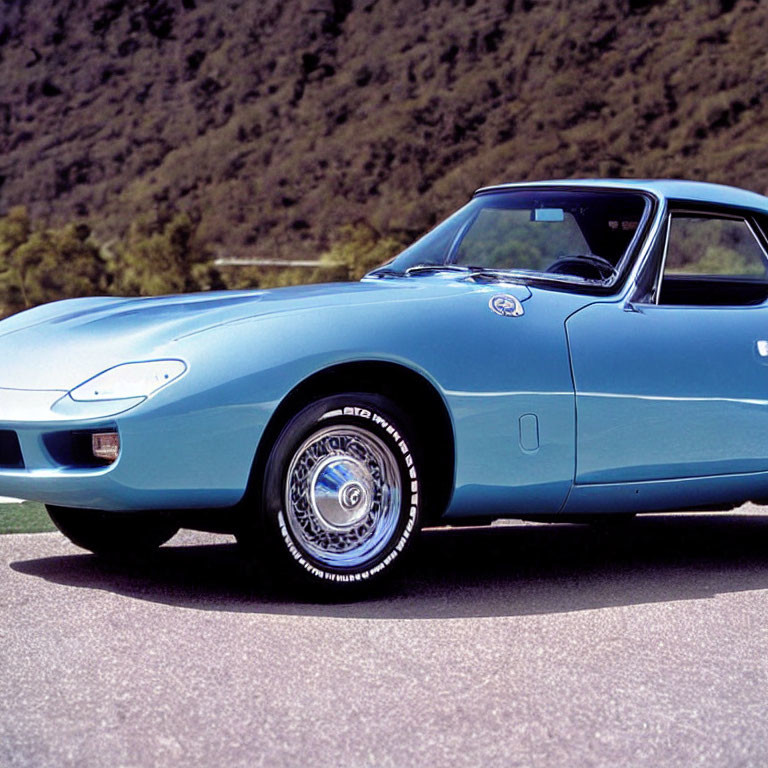 Vintage Blue Sports Car with Pop-Up Headlights and Chrome Wheels Outdoors