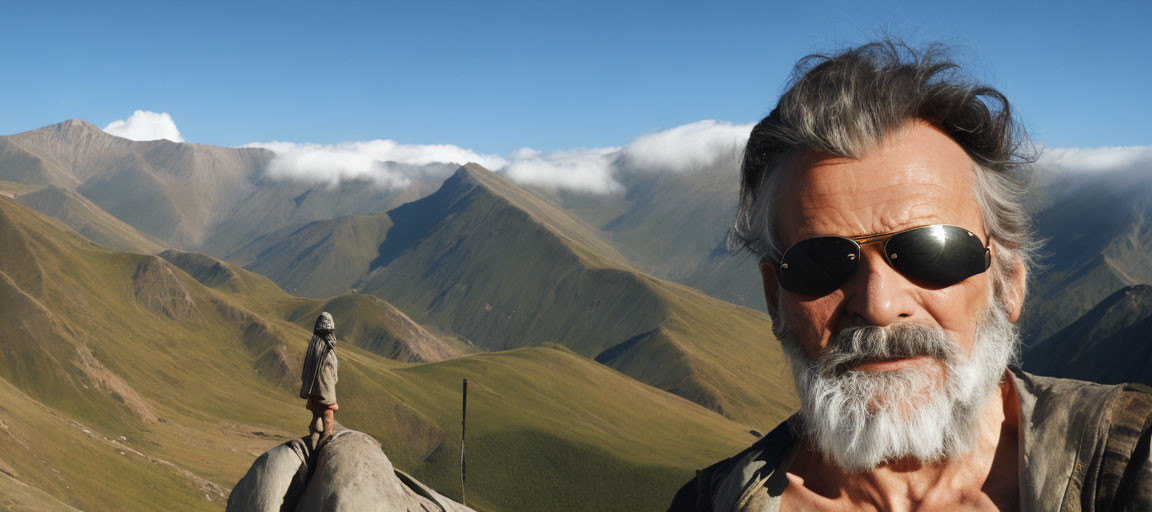 Bearded man with sunglasses against mountain backdrop