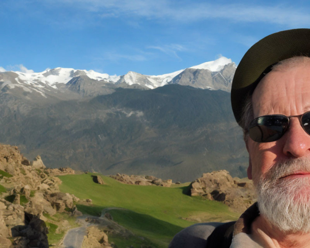 Bearded man in sunglasses takes selfie with mountains and valley backdrop