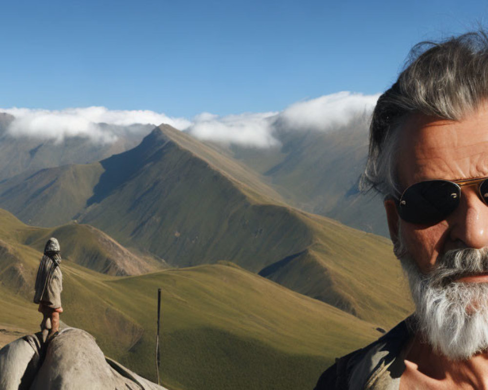 Bearded man with sunglasses against mountain backdrop