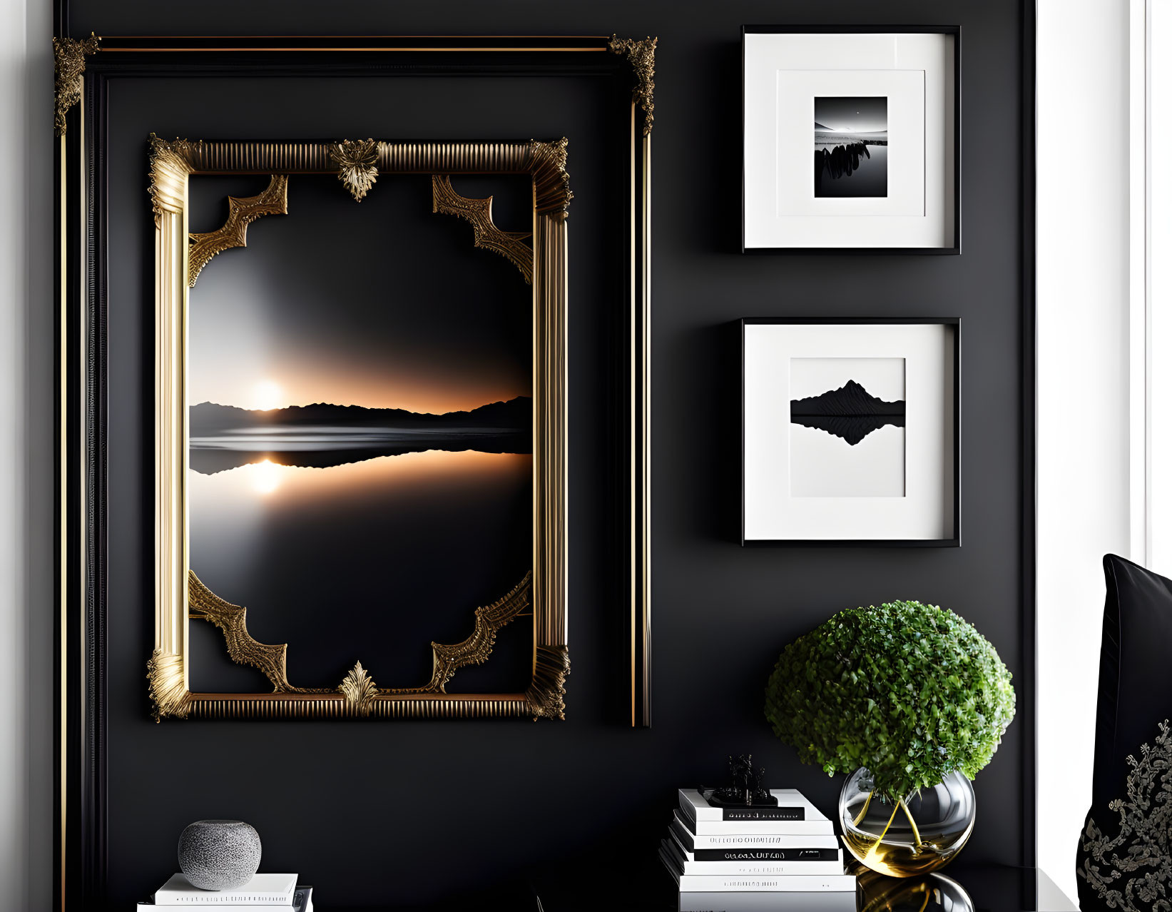 Golden frame with scenic sunset on black wall, flanked by white artworks, books, and plant.