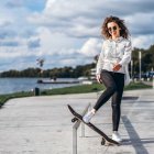 Animated girl in black hair and white/blue outfit on riverside path