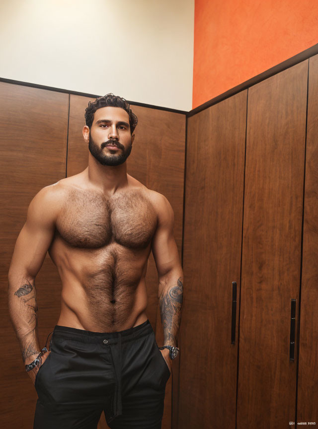 Muscular man with tattoos stands confidently in front of wooden locker background